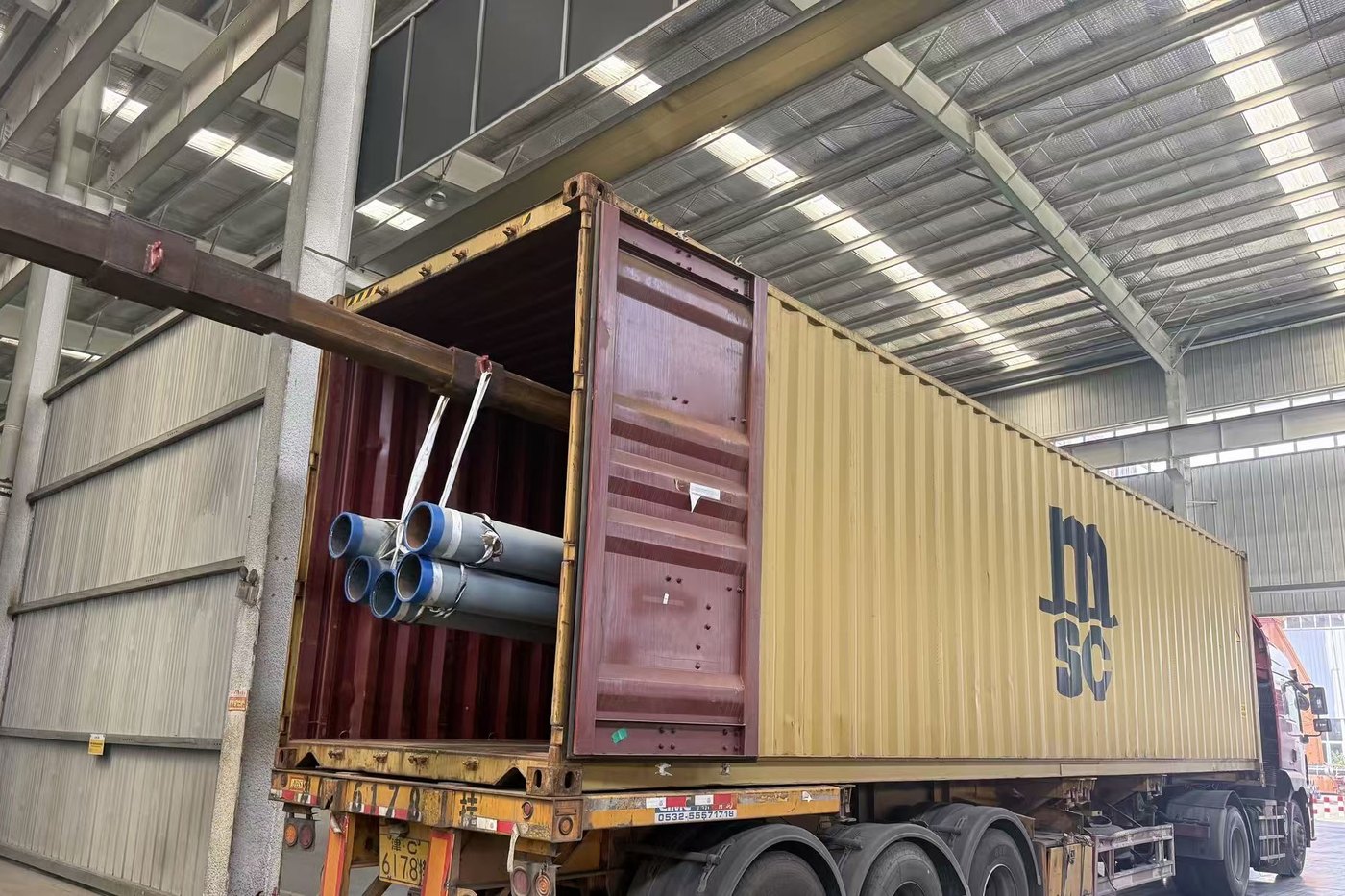 Steel pipe being loaded into a shipping container